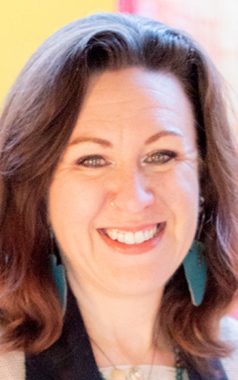 White woman with green earrings and auburn hair