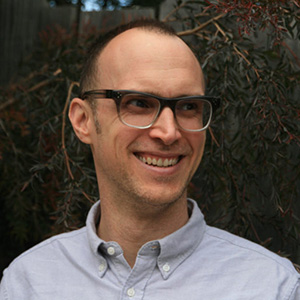 White man with ombre colored spectacles and a blue button-down shirt