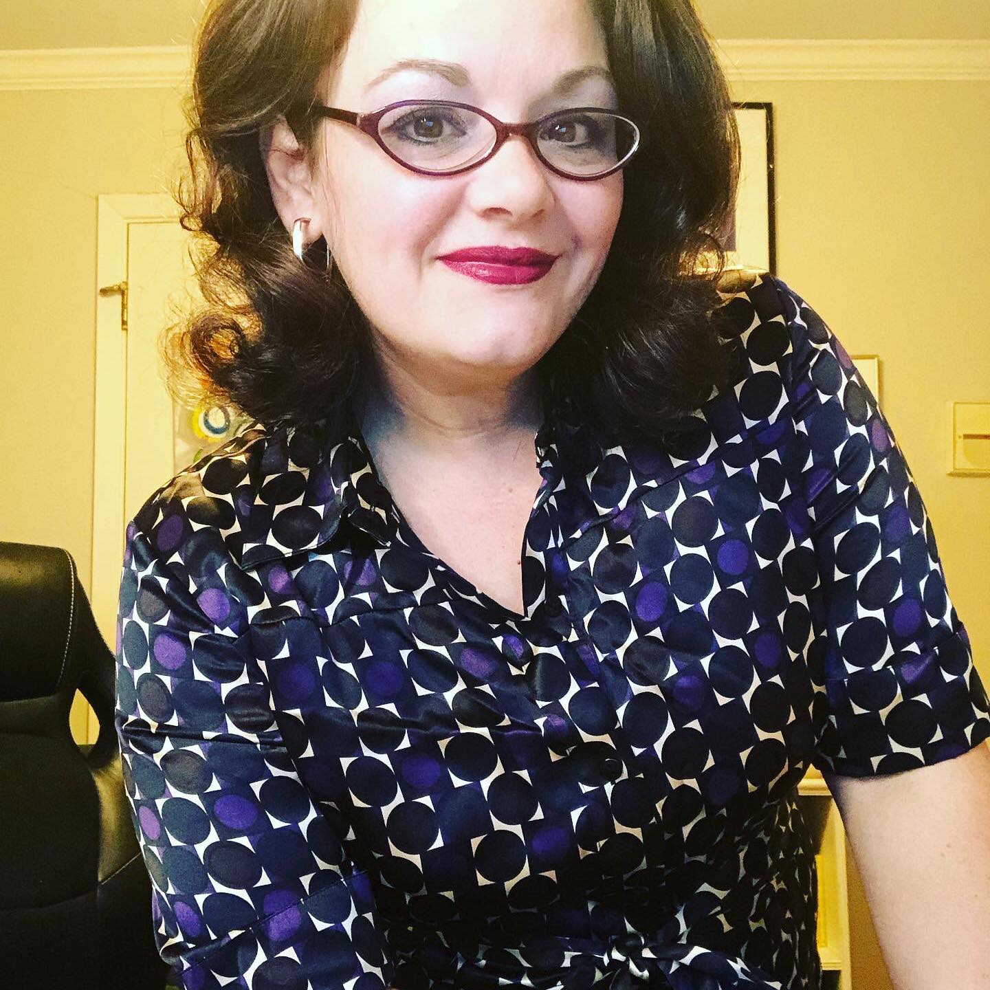 White woman woman spectacles, red lipstick, and blue and purple blouse
